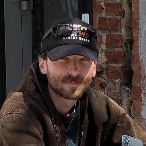 a man sitting on a sidewalk with his dog
