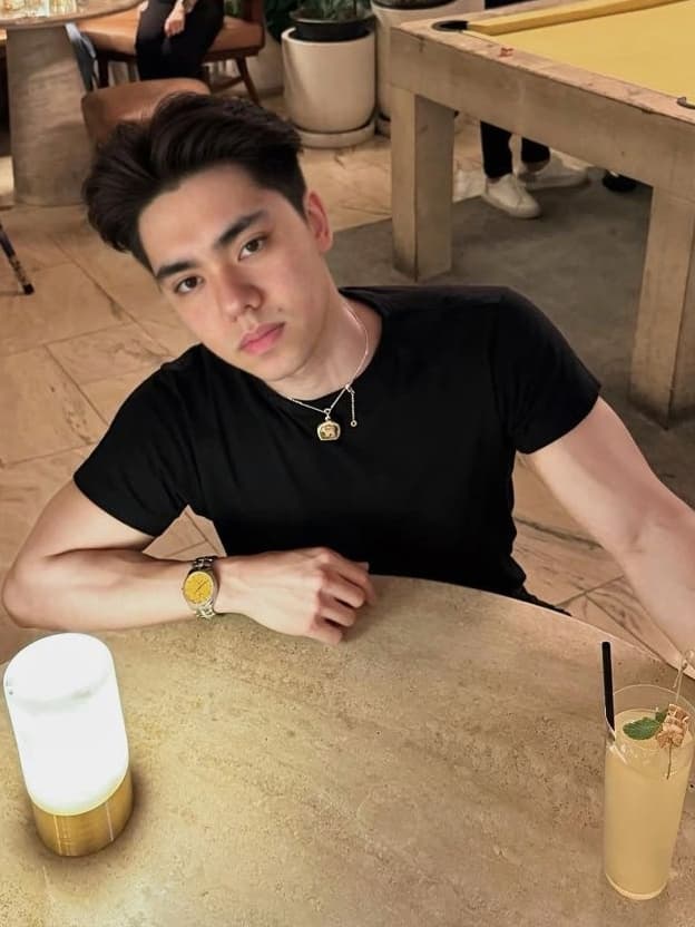 Matthew Stevens in a black T-shirt seated at a table in a cafe.