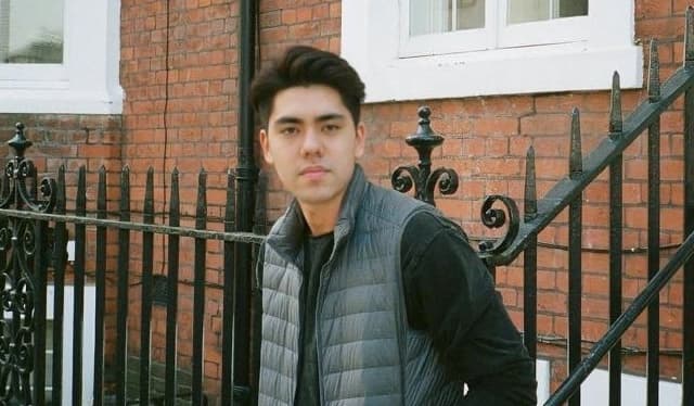 A man in a puffer vest in front of a London townhouse.