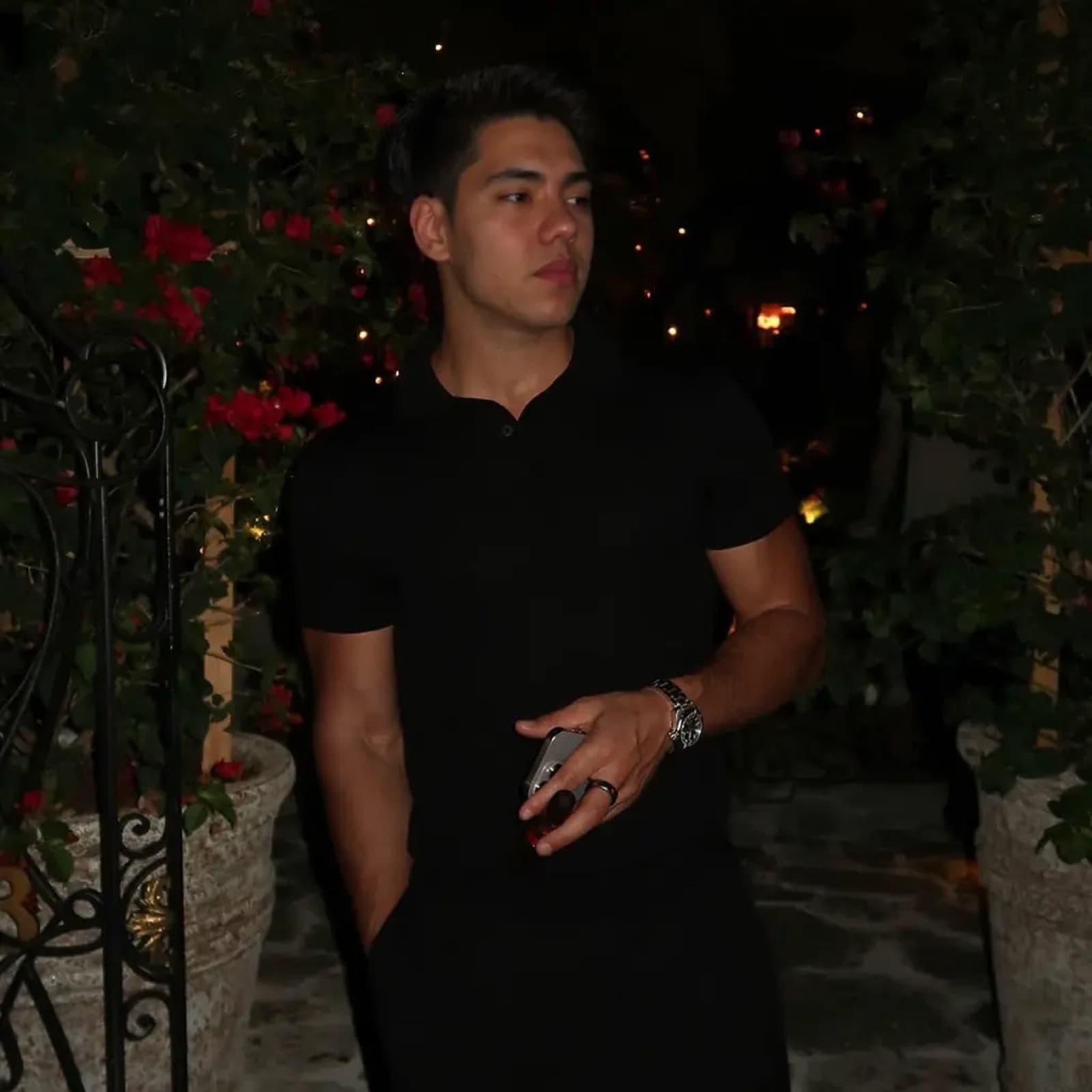 Matthew Stevens in a black outfit among flowers at night.