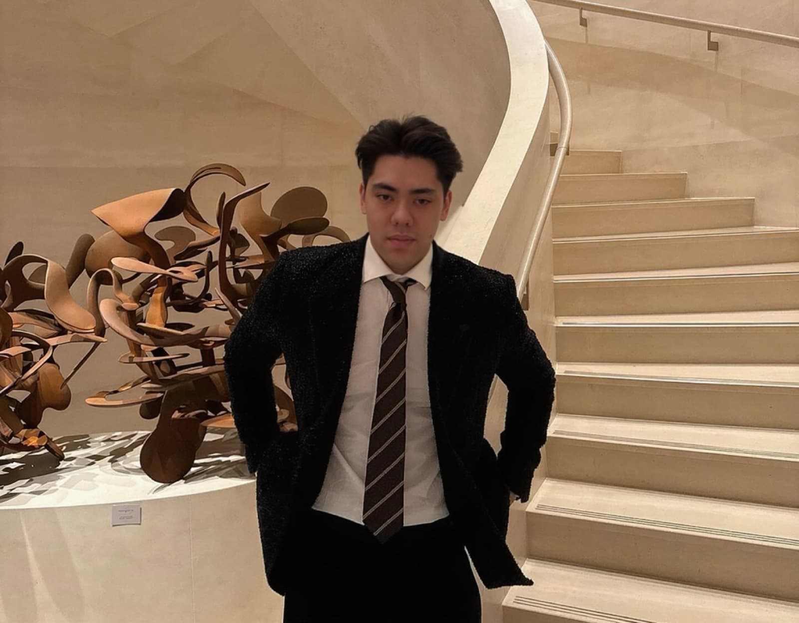 A stylish man in a suit by an elegant staircase.