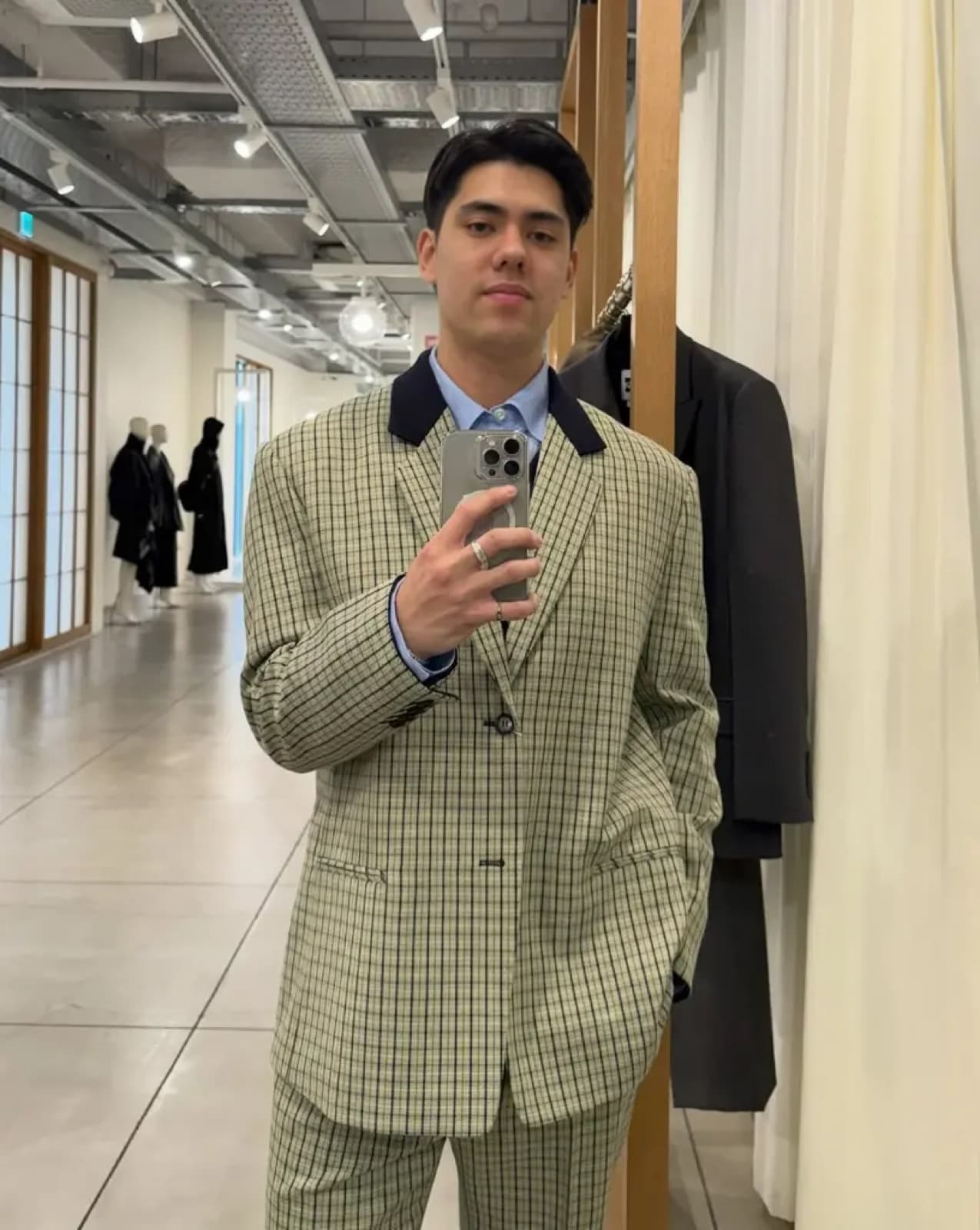 A man in a checkered suit taking a mirror photo.