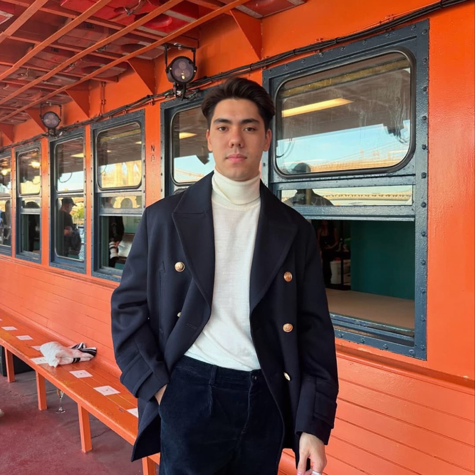A young man in a navy coat and white turtleneck.